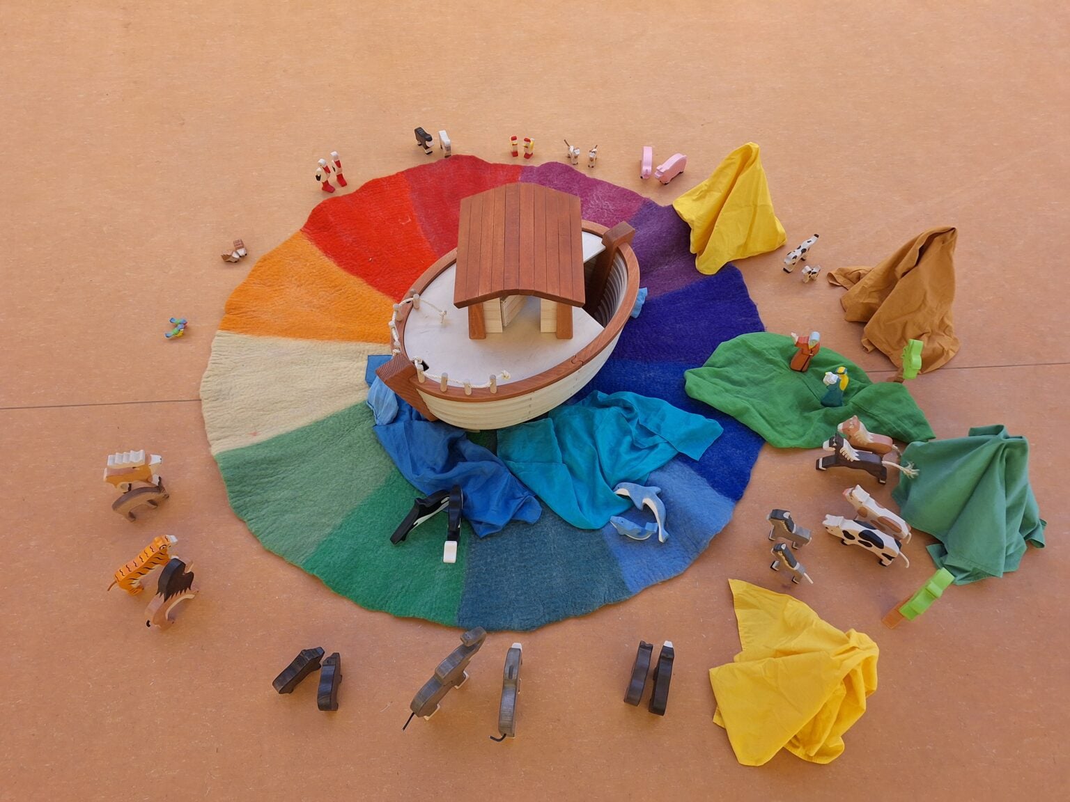 Holzarche mit Tierfiguren auf einem Filzkreis in Regenbogenfarben – aus einer Andacht im Kindergarten Arche Noah